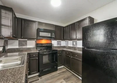Renovated kitchen inside Hillwood Villas Apartments in Knoxville, TN featuring espresso cabinetry and clean black appliances.